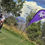 a banner with the infinite hero logo sits behind a man golfing