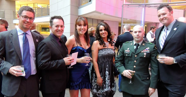 a group of people in suits and dresses smile at the camera