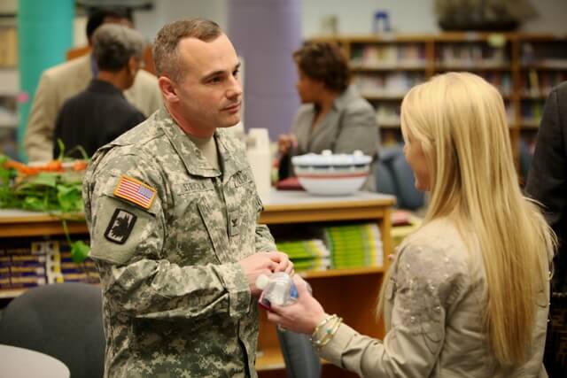 a man in an army uniform talks to a lady with blonde hair